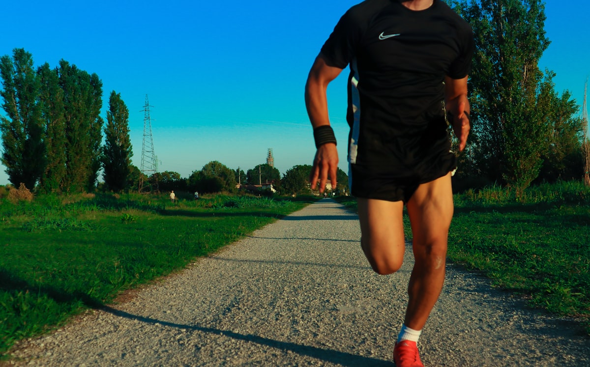 Runner in salita verso i 10K, espressione concentrata ma determinata; sfondo urbano o parco.