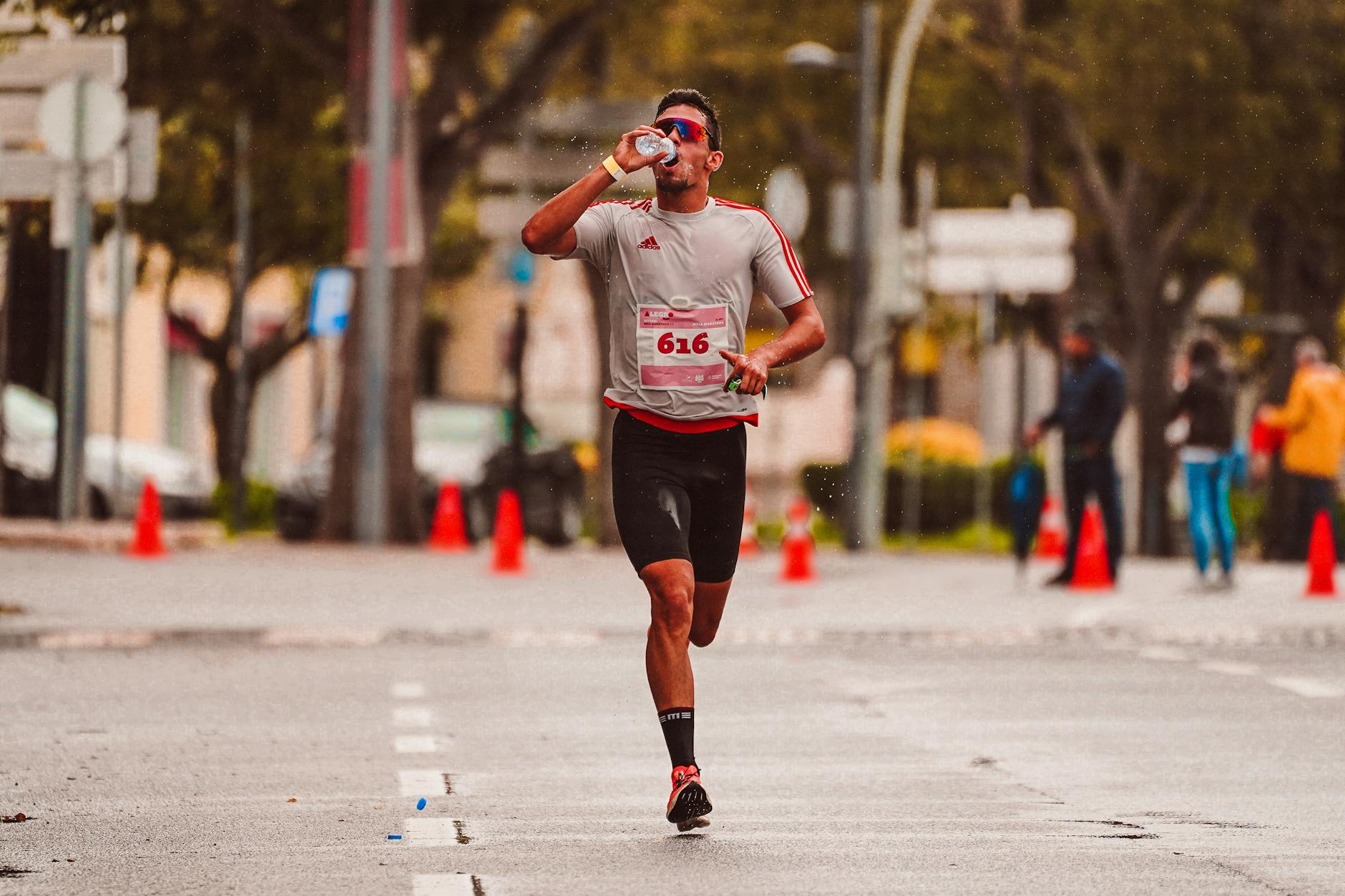 runner drinking from water bottle on sunny trail, refreshing
