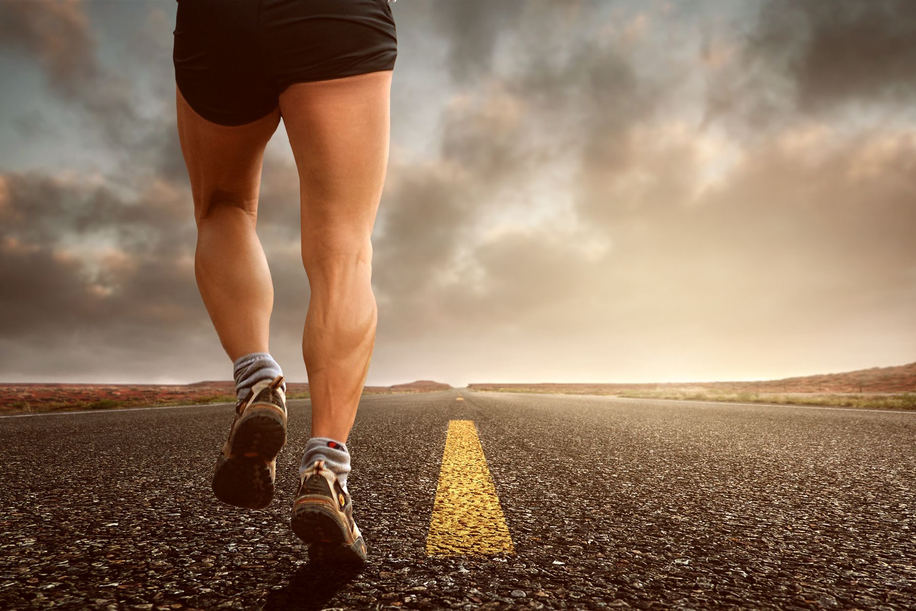runner on park bench looking at running shoes, contemplating return