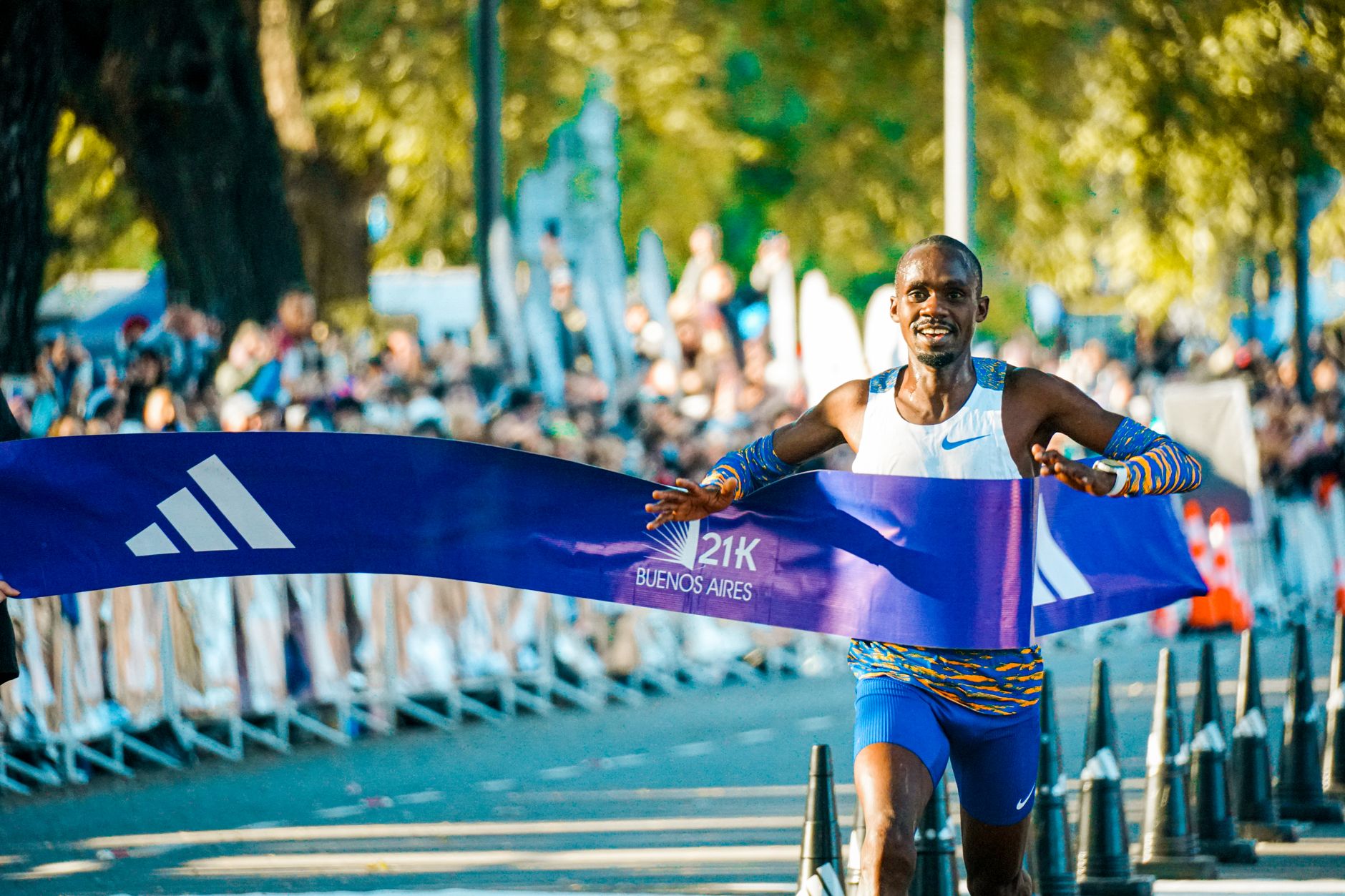 Runner che taglia il traguardo della mezza maratona, medaglia al collo, emozione autentica sul viso.